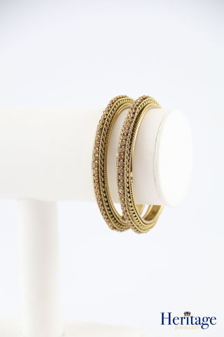 Intricately designed antique gold bangles adorned with crystals