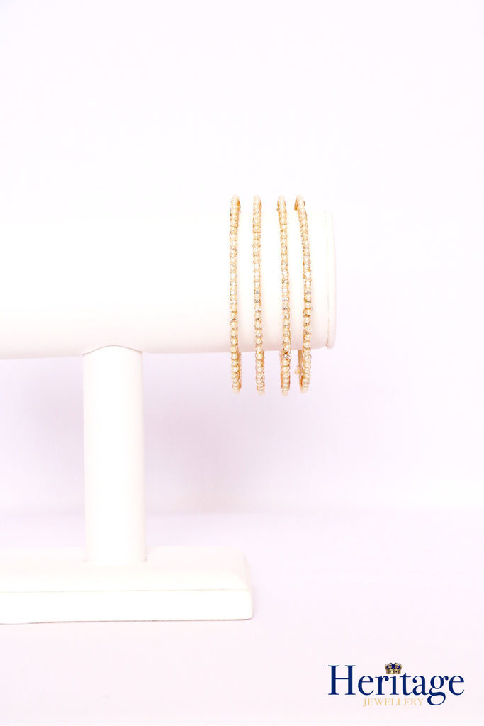 Rose gold bangles adorned with silver crystals and pearls.