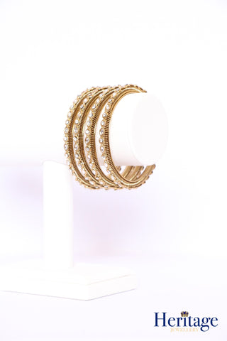 Intricately designed antique gold bangles adorned with crystals