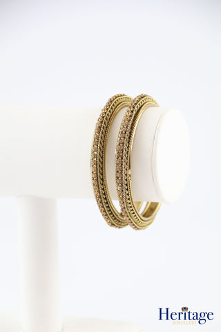 Antique gold bangles adorned with silver crystals.